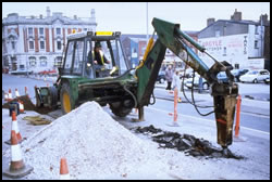 Mounted breaker being used to break roadway