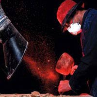 In this image, special lighting and photography have been used to show the plume of dust that is made when this stonemason chisels a stone block