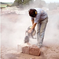 a worker is cutting a block of stone using a petrol engine driven cutting disc