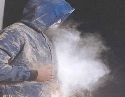 Person wearing boilersuit covered with dust and dust in the air