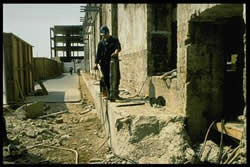 Hydraulic bursting tool being used to demolish a retaining wall