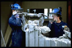 workers using a concrete crusher to crush a wall