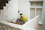 Person in hi-viz acessing bin in walled house courtyard