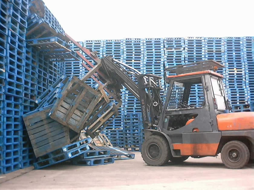 Forklift truck pulling pallets from high stacks and pallets falling on ground